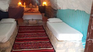 Ein gemütliches Zimmer mit zwei Betten, einem gemusterten Teppich und einer Steinwand.
