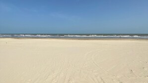 Ein sandiger Strand mit Fußabdrücken, die zum Wasser führen.