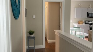 A hallway with wooden flooring, a teal wall decoration, and a small table with a plant. - Sebago Lake, Maple Cove, Lake House (Casco)