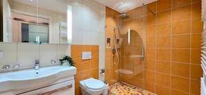 A modern bathroom with a white sink, mirror, and shower.