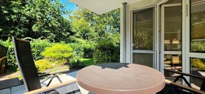 A round table with chairs on an outdoor patio with a view of dense greenery.