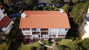 En byggnad med flera våningar, ett rött tegeltak, satellitantenner och balkonger.
