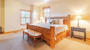 Een slaapkamer met een houten bed, een bankje, twee nachtkastjes en een raam met zonwering.