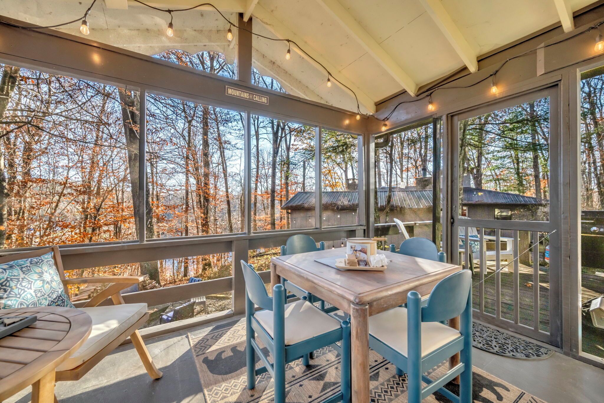 A cozy outdoor seating area with a table and chairs, overlooking a forested landscape.