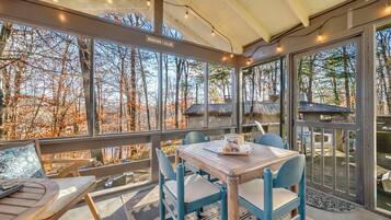 A cozy outdoor seating area with a table and chairs, overlooking a forested landscape.