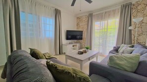Een woonkamer met een flatscreen televisie, een bijzettafeltje en een bank.