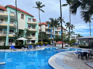 Ein Resort mit Schwimmbad, Liegestühlen und Palmen.