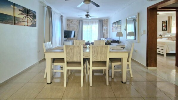 A dining area with a table and chairs, a ceiling fan, and a television. - Lovely Spacious Condo with Pool View, Close to Beaches and Shops! (Punta Cana)