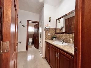 A bathroom with a wooden vanity, a sink, a mirror, and a toilet. - Lovely Spacious Condo with Pool View, Close to Beaches and Shops! (Punta Cana)