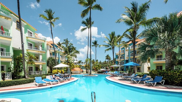 A resort pool with lounge chairs and palm trees.