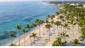 A beach with palm trees and blue lounge chairs. - Lovely Spacious Condo with Pool View, Close to Beaches and Shops! (Punta Cana)
