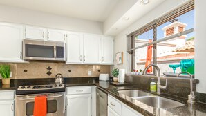 A modern kitchen with white cabinets, stainless steel appliances, a granite countertop, and a window with a view of the outside. - Beautiful 2 Bedroom 2 Bath Scottsdale Townhome (Scottsdale)