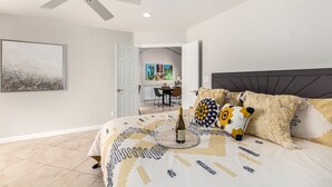 A bedroom with a bed, a ceiling fan, a dining area, and a kitchen in the background. - Beautiful 2 Bedroom 2 Bath Scottsdale Townhome (Scottsdale)