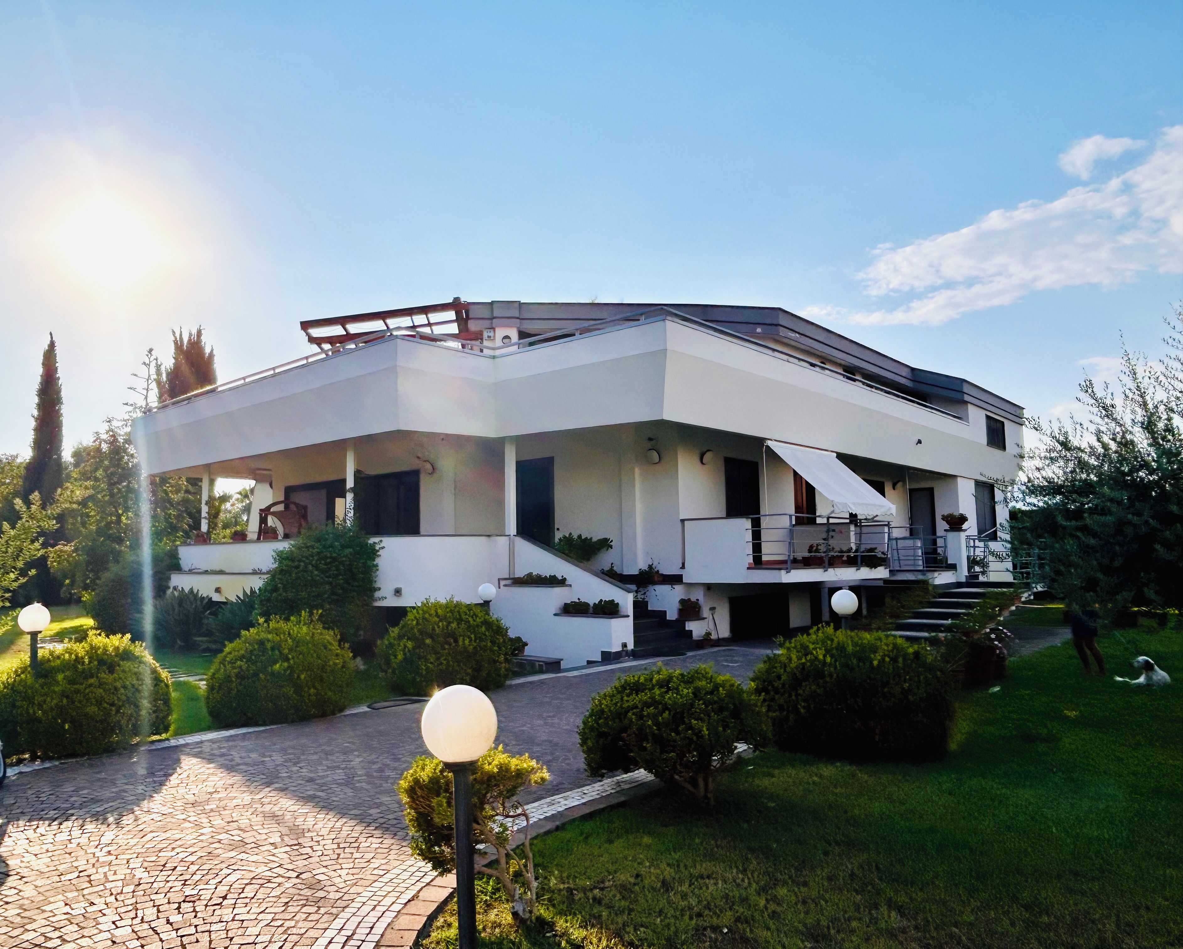 A modern two-story house with a flat roof, a covered porch, and a paved driveway.