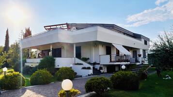 A modern two-story house with a flat roof, a covered porch, and a paved driveway.