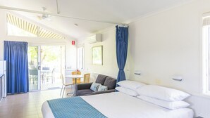 Habitación de hotel moderna con cama, mesita de noche, ventilador de techo y vistas al exterior.