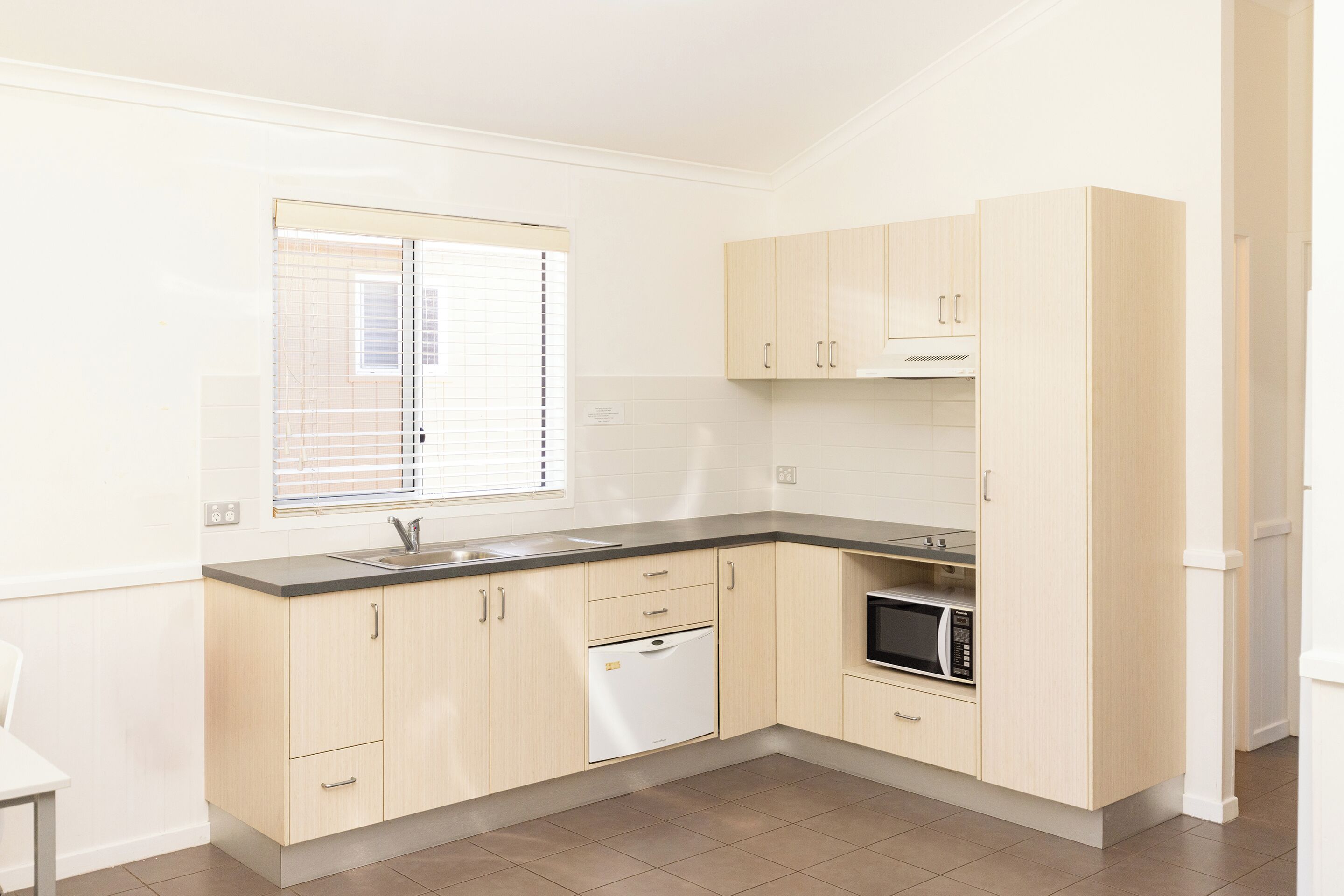 A modern kitchen with light wood cabinets, a built-in microwave, and a dishwasher.