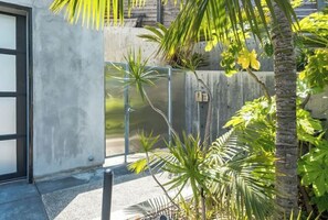 A modern building with a concrete facade, a metal gate, and tropical plants.