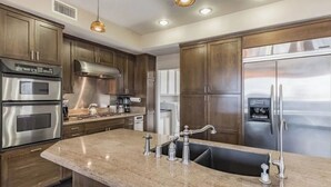 A modern kitchen with stainless steel appliances, wooden cabinets, and a granite countertop. - Ocean view Surf Ghetto custom home (San Clemente)