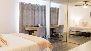 Ein Hotelzimmer mit einem großen Bett, einem Schreibtisch, einem Sessel und einem Spiegel.