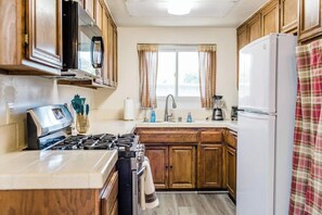 A kitchen with wooden cabinets, a stove, a refrigerator, a sink, and a window with curtains. - 3 BD / Family Friendly / Great Location (Torrance)