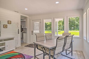 Enjoy meals in this dining area with a large table and four chairs, offering a view of the lush green landscape.