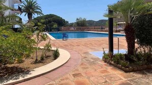 Una piscina con un sendero de piedra, rodeada de follaje y un edificio.