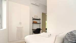 Ein Hotelzimmer mit einem Bett, einem Schrank, einer Ablagefläche mit einem Bilderrahmen und einem Sessel.