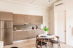 Uma cozinha moderna com eletrodomésticos de aço inoxidável, armários de madeira, uma mesa de jantar redonda com cadeiras e um vaso de planta.
