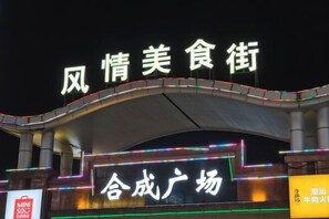 A building with illuminated signage reading "风情美食街" and "合成广场". - Vienna Hotel Guangzhou Huadu Cultural Tourism City Shiling shop (Guangzhou)