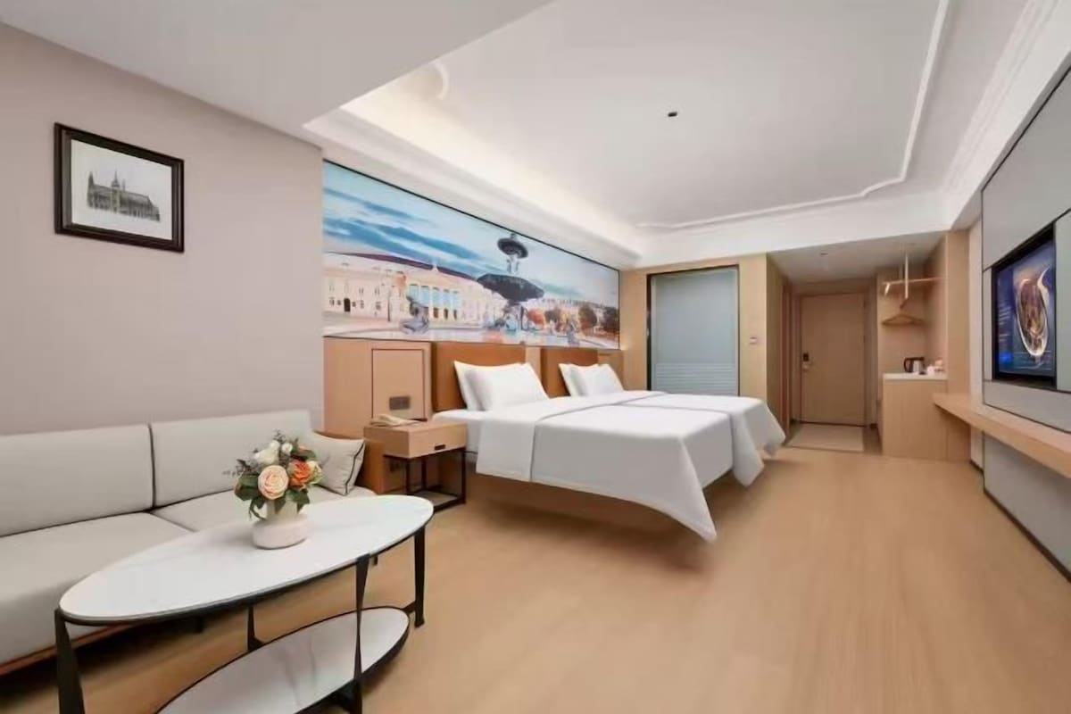 A hotel room with a bed, a sofa, a table, and a painting on the wall.