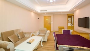 A hotel room with a sofa, armchair, small table, bed, TV, and a door leading to a bathroom. - Vienna Hotel Guangzhou Huadu Cultural Tourism City Shiling shop (Guangzhou)