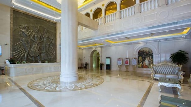 A spacious lobby with a large central column, a decorative wall, and a seating area with ornate furniture. - Vienna Hotel Guangzhou Huadu Cultural Tourism City Shiling shop (Guangzhou)