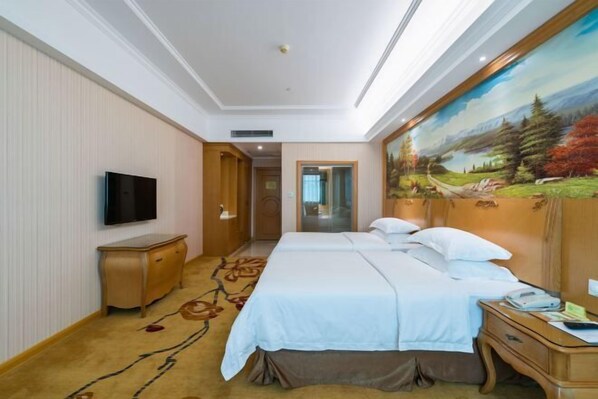 A hotel room with a large bed, a TV mounted on the wall, a wooden nightstand, and a painting on the wall. - Vienna Hotel Guangzhou Huadu Cultural Tourism City Shiling shop (Guangzhou)