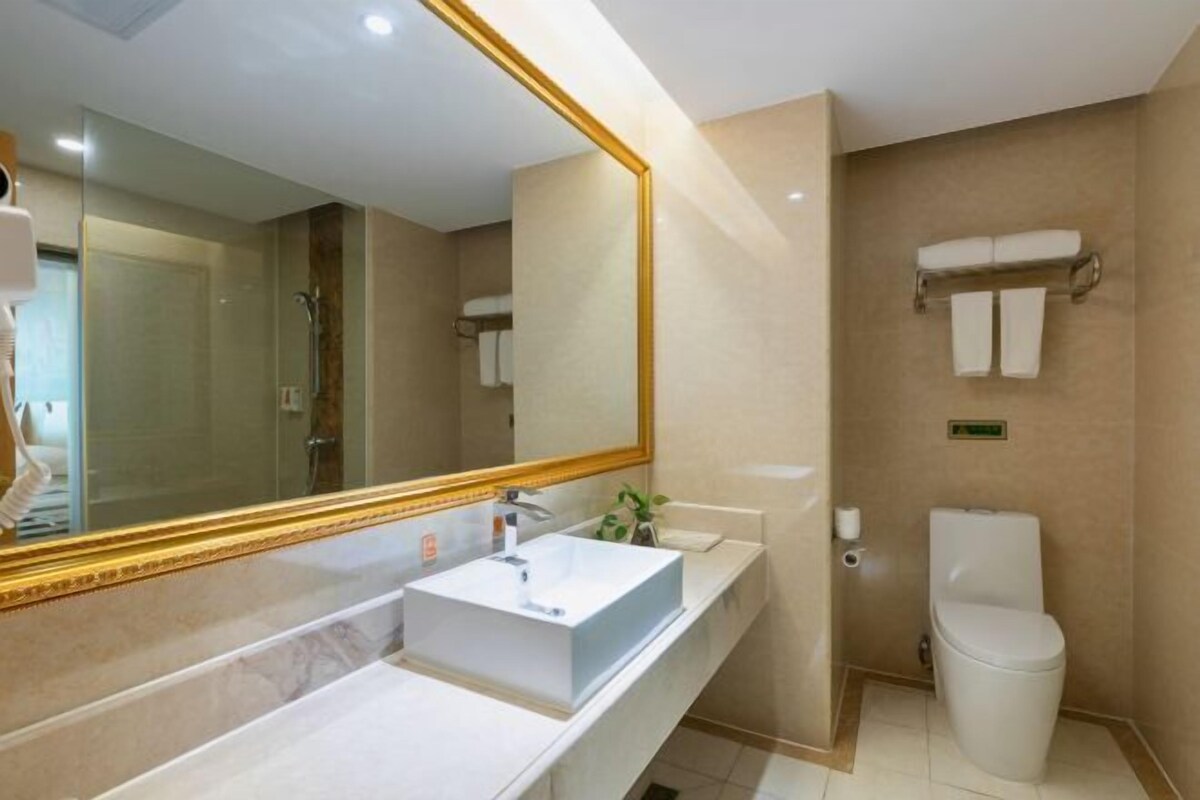 A modern bathroom with a large mirror, a white sink, and a toilet.