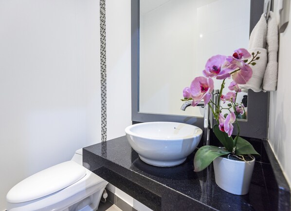 A modern bathroom with a white sink, a toilet, and a mirror above the sink.
