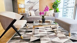 Ein modernes Wohnzimmer mit einer Couch, Sesseln, einem Couchtisch und einer Topfpflanze.