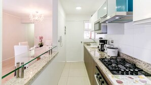Eine moderne Küche mit Glastrennwand, Edelstahlgeräten und einer Arbeitsplatte aus Granit.