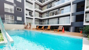 Ein modernes Gebäude mit Swimmingpool, mehreren Balkonen und Sitzbereichen im Freien.