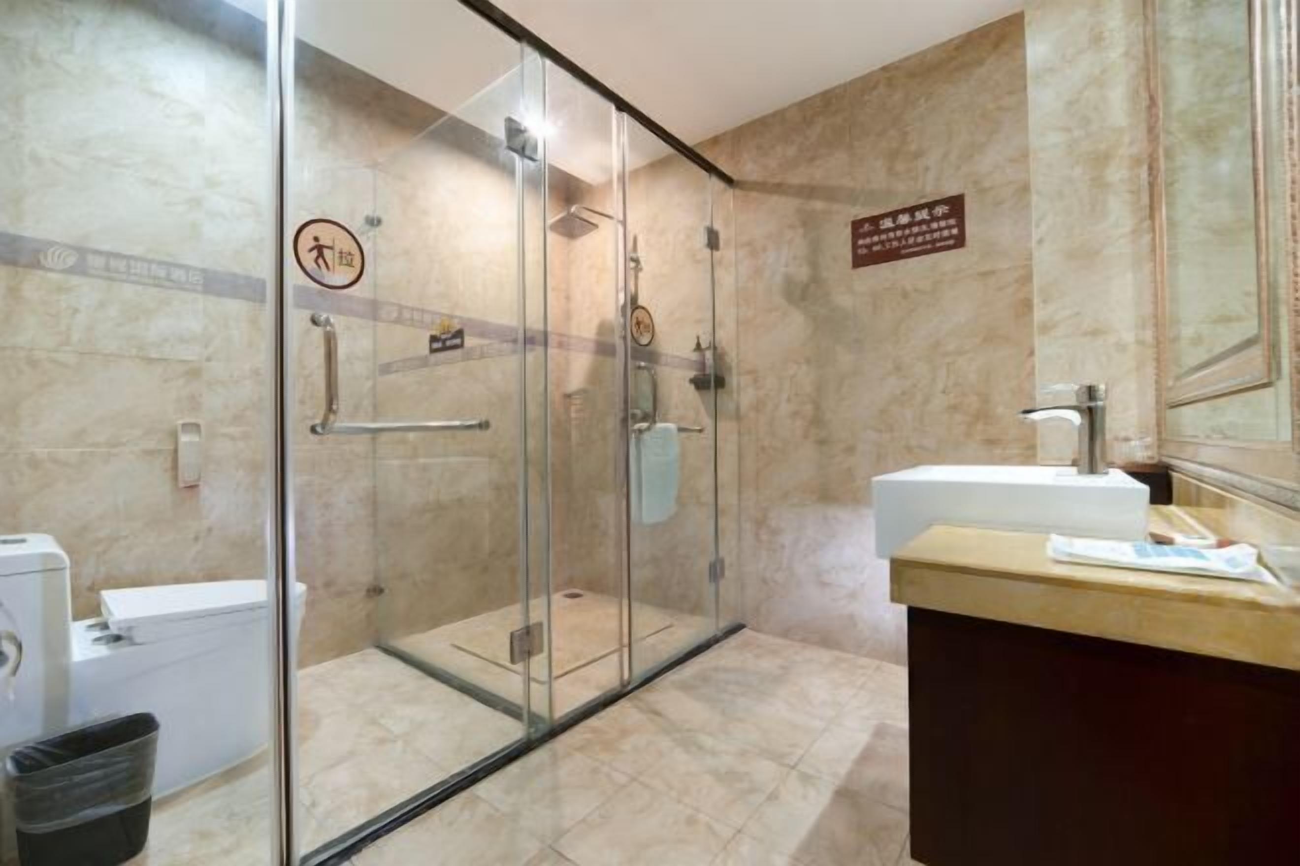 A modern bathroom with a glass-enclosed shower, a white sink, and a marble-tiled floor.