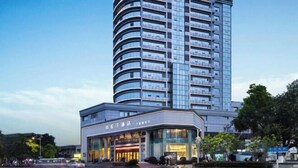 A modern hotel with a curved facade, multiple floors, and a prominent entrance with glass doors. - Dilunting International Hotel (Wansheng Yaocheng) (Chongqing)