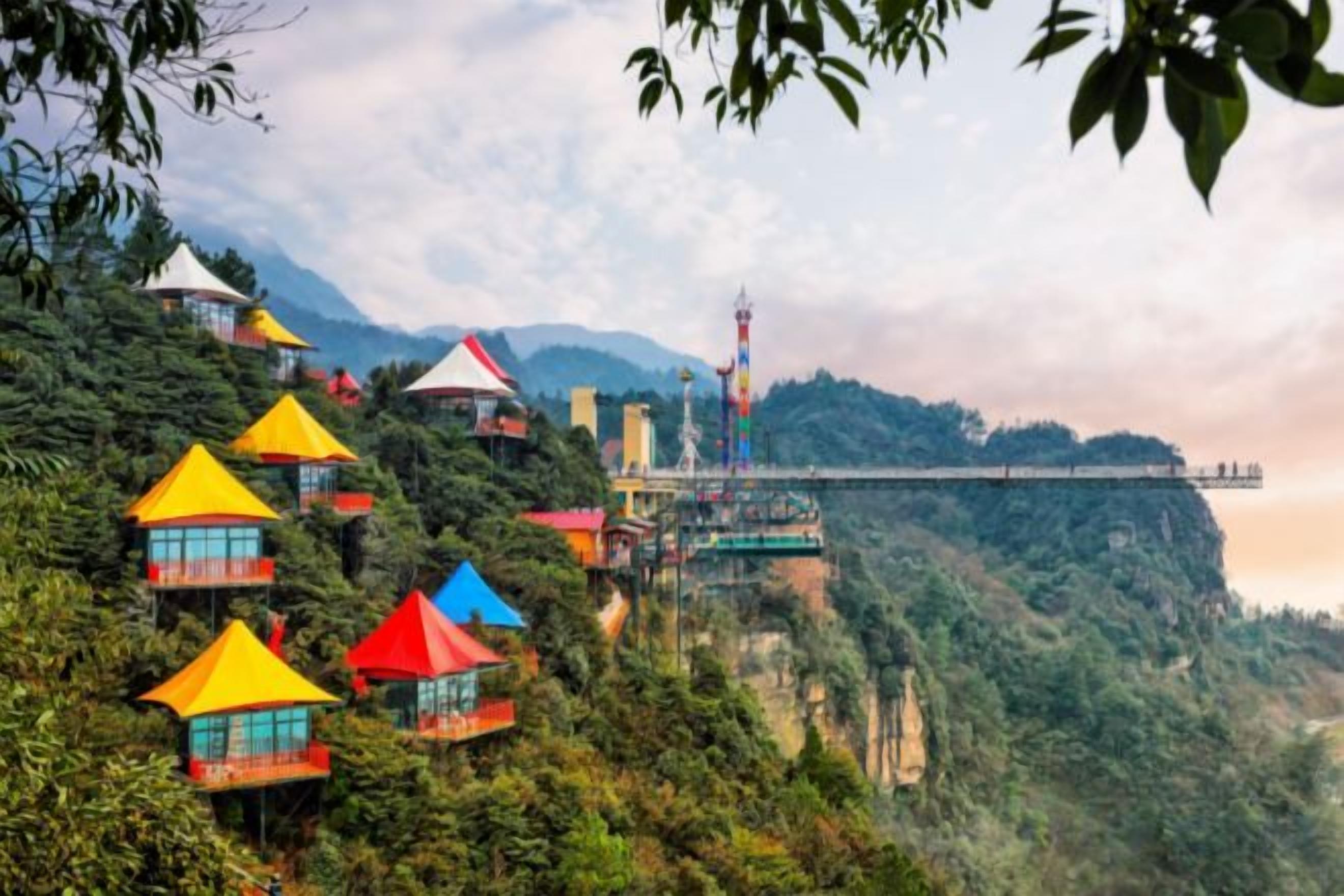 Conjunto de edificios coloridos y de varios niveles en una ladera, con un puente al fondo.