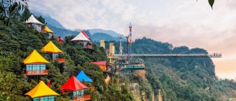 A series of colorful, multi-level buildings on a hillside with a bridge in the background.
