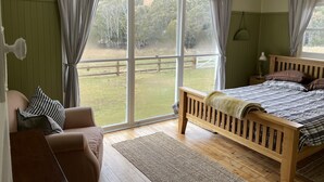 Ein Schlafzimmer mit einem hölzernen Bett, einer Couch und großen Fenstern.