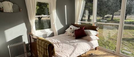 Une chambre à coucher avec un lit, un radiateur, une fenêtre et une vue sur l’extérieur.