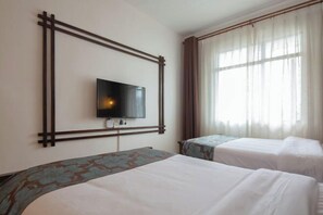 Habitación de hotel con dos camas, un televisor instalado en la pared y una ventana con cortinas.