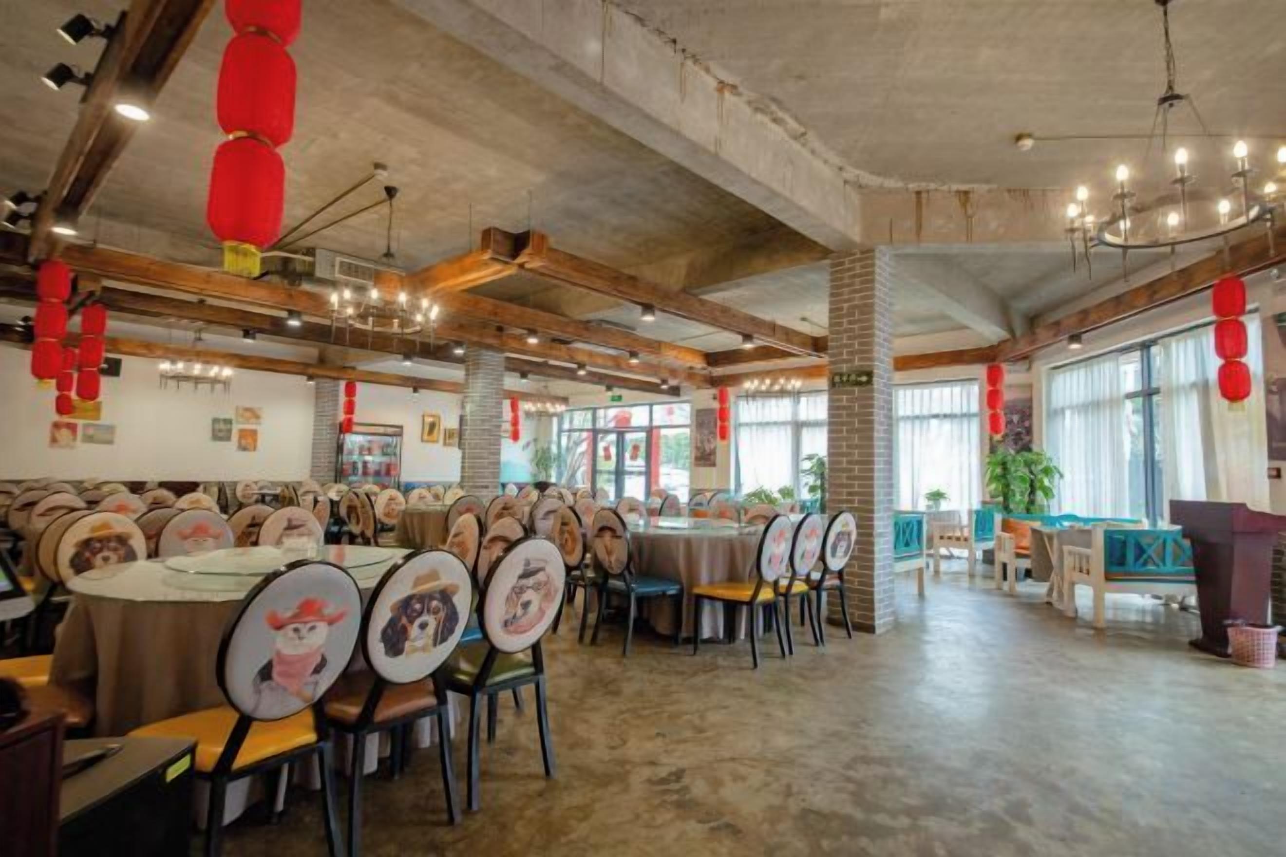 Un restaurante espacioso con techos altos, vigas a la vista y una combinación de mesas redondas y cabinas.