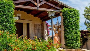 A traditional building with a wooden roof, a stone entrance, and a garden with colorful flowers.