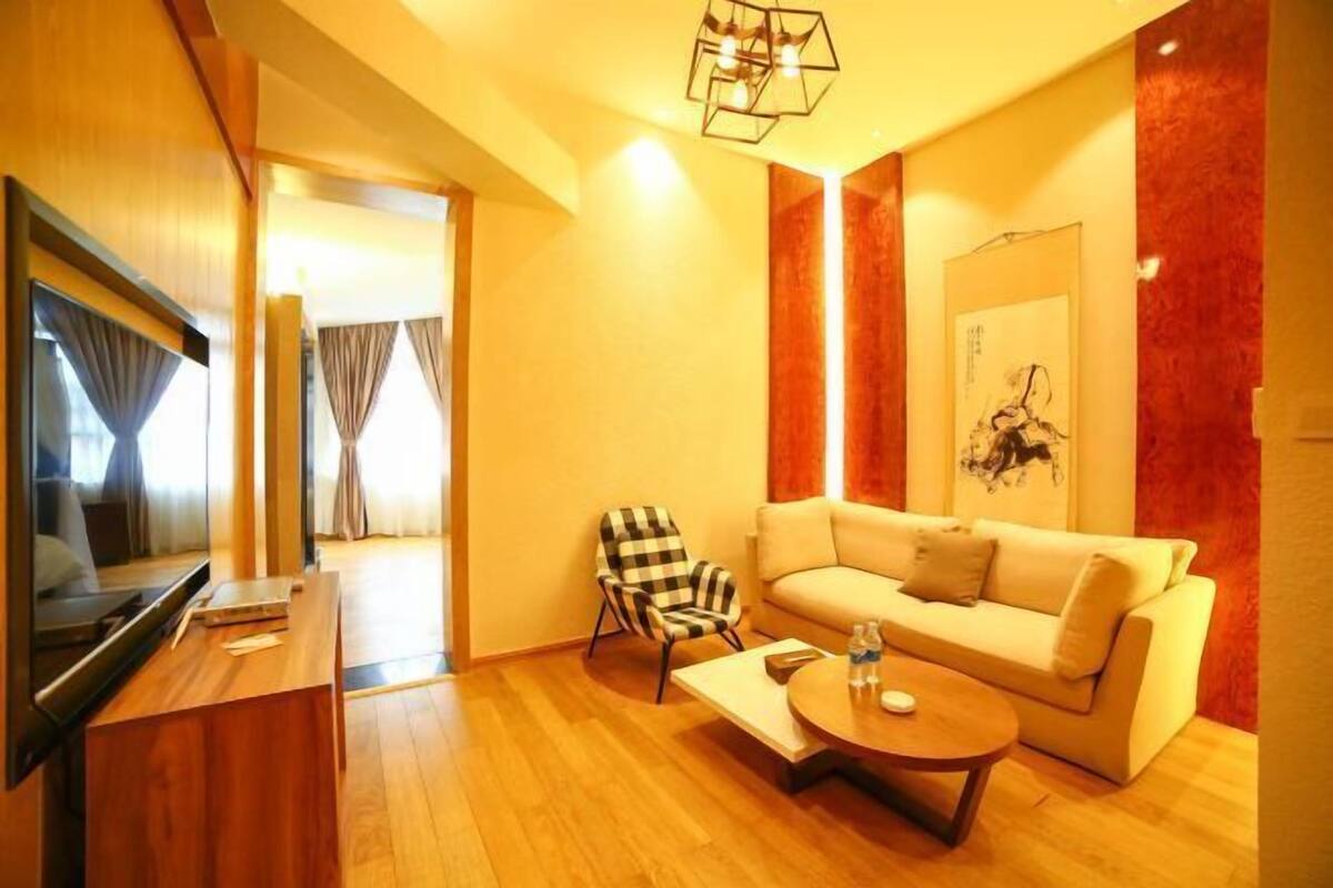 A living room with a sofa, armchair, coffee table, flat-screen TV, and artwork on the wall.