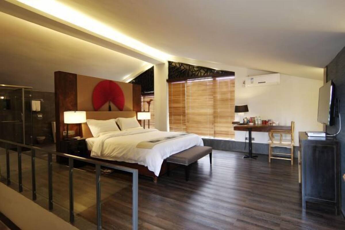 A modern hotel room with a large bed, bedside tables, a desk, and a TV.